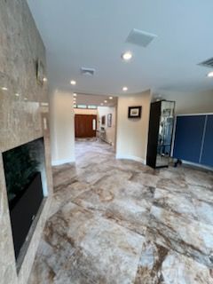A modern living room with marble floors, a TV, and a hallway leading to a door.