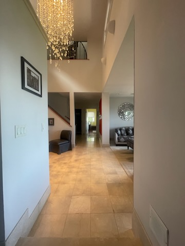Hallway with marble floor, chandelier, and a view into living areas.