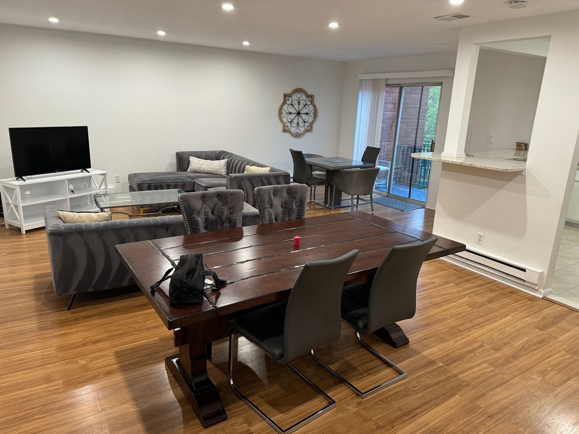 A living room with a table and chairs and a clock on the wall.