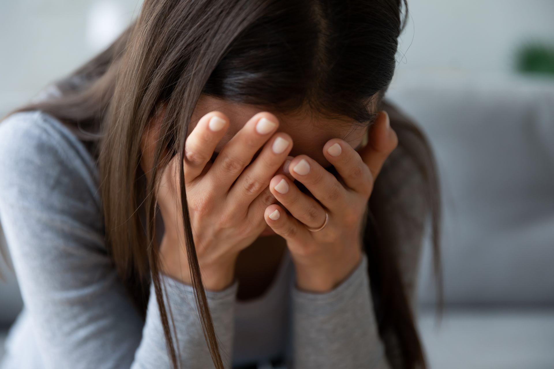 Woman with hands covering her face, appearing distressed.