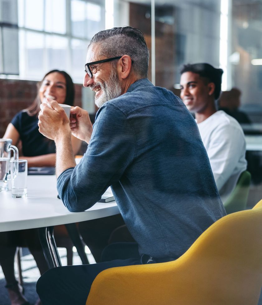 A man with glasses is sitting at a table with other people.