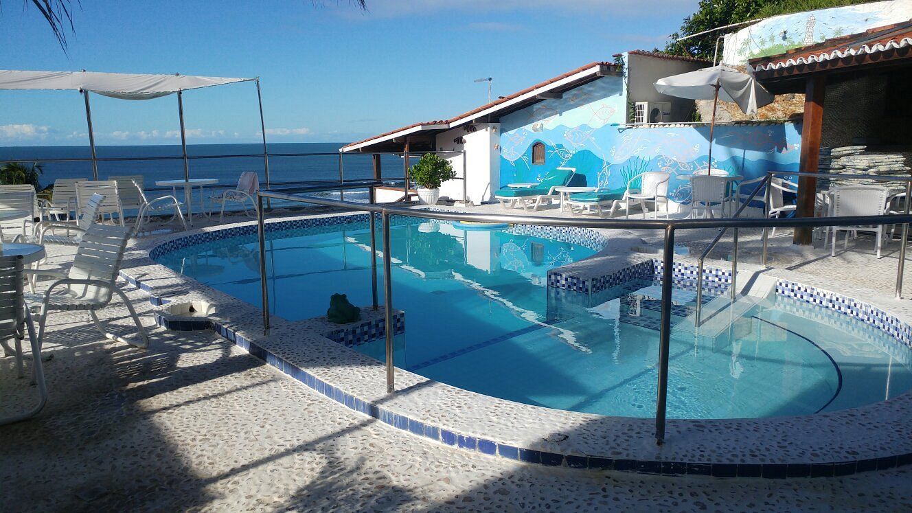 Uma grande piscina cercada por cadeiras e mesas com vista para o oceano.