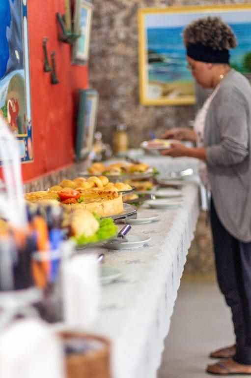Uma mulher está parada em frente a uma longa mesa cheia de comida.
