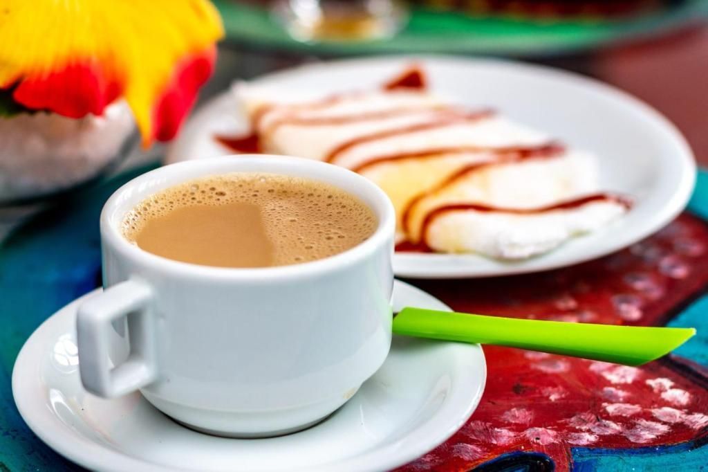 Uma xícara de café está em um pires ao lado de um prato de comida.