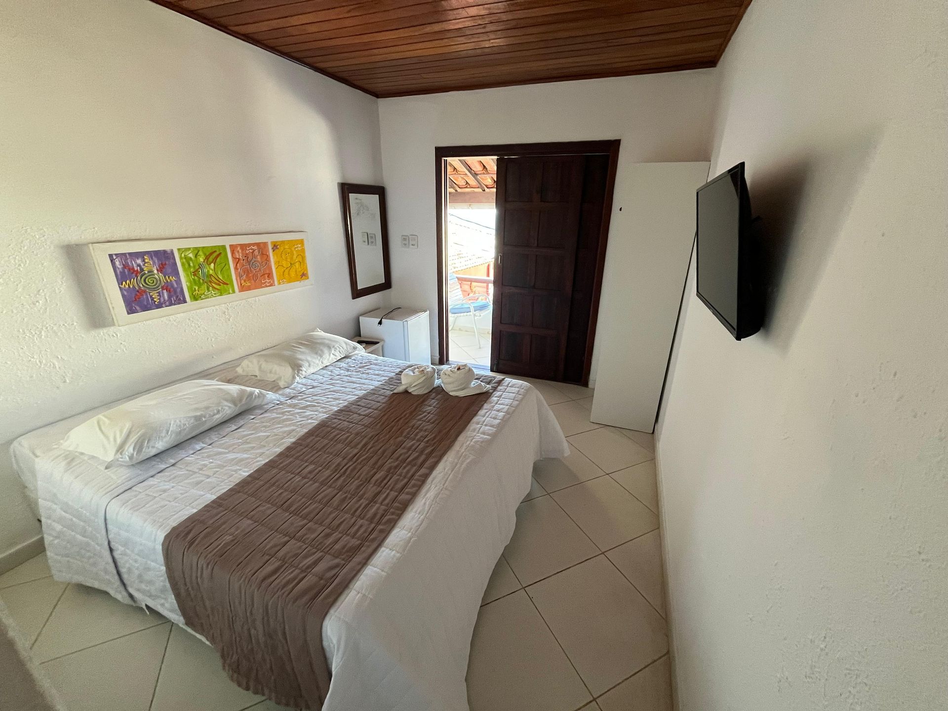 Um quarto com uma cama e uma televisão na parede.