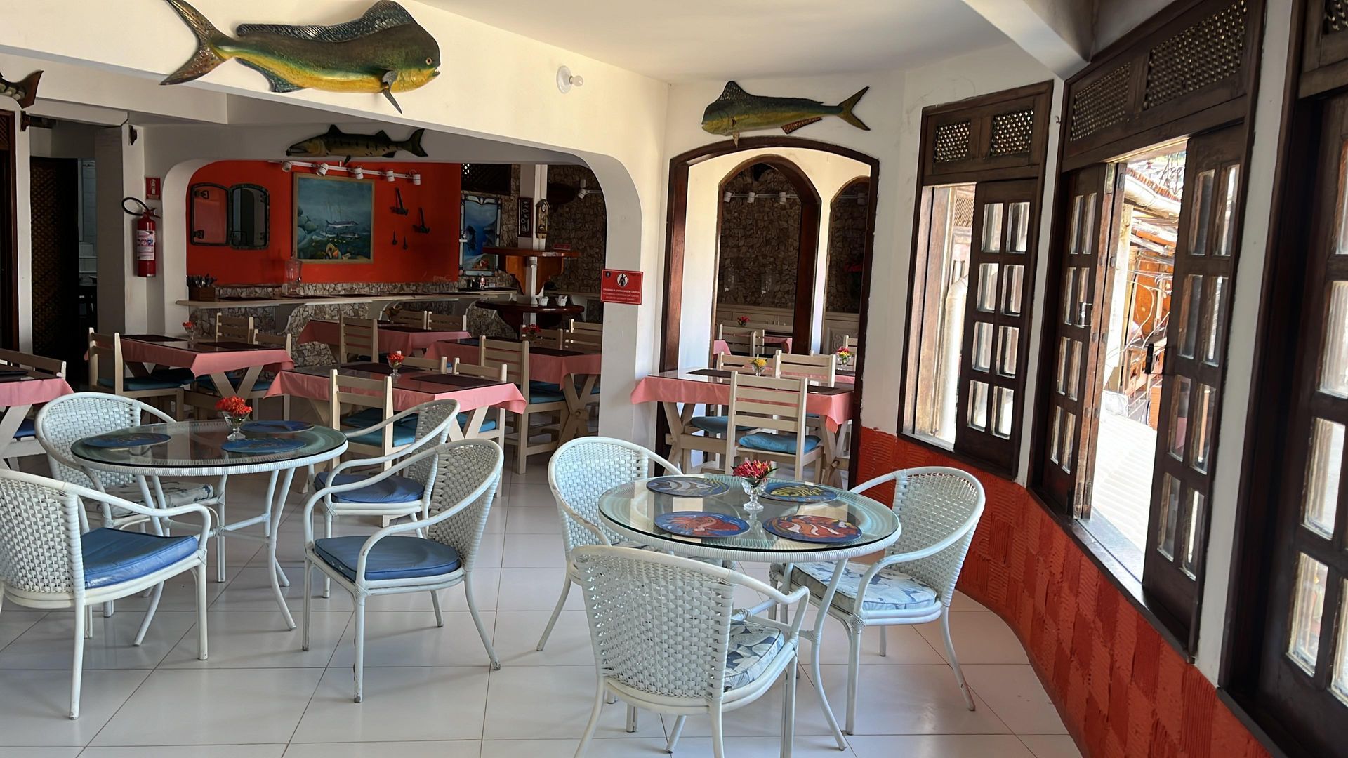 Um restaurante com mesas e cadeiras e um peixe no teto.