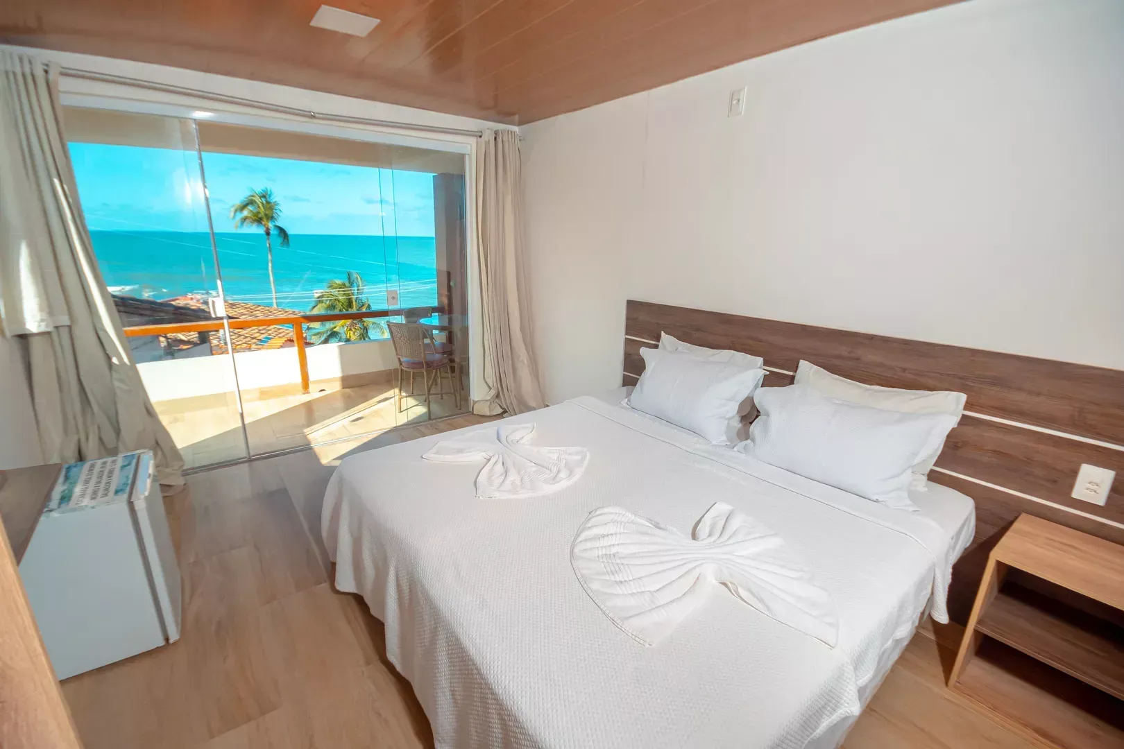 Um quarto de hotel com uma cama grande e uma varanda com vista para o oceano.