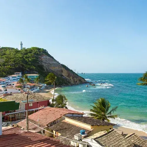 Uma vista aérea de uma praia com um farol ao fundo
