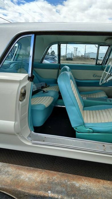 The inside of a white and blue car with the door open.