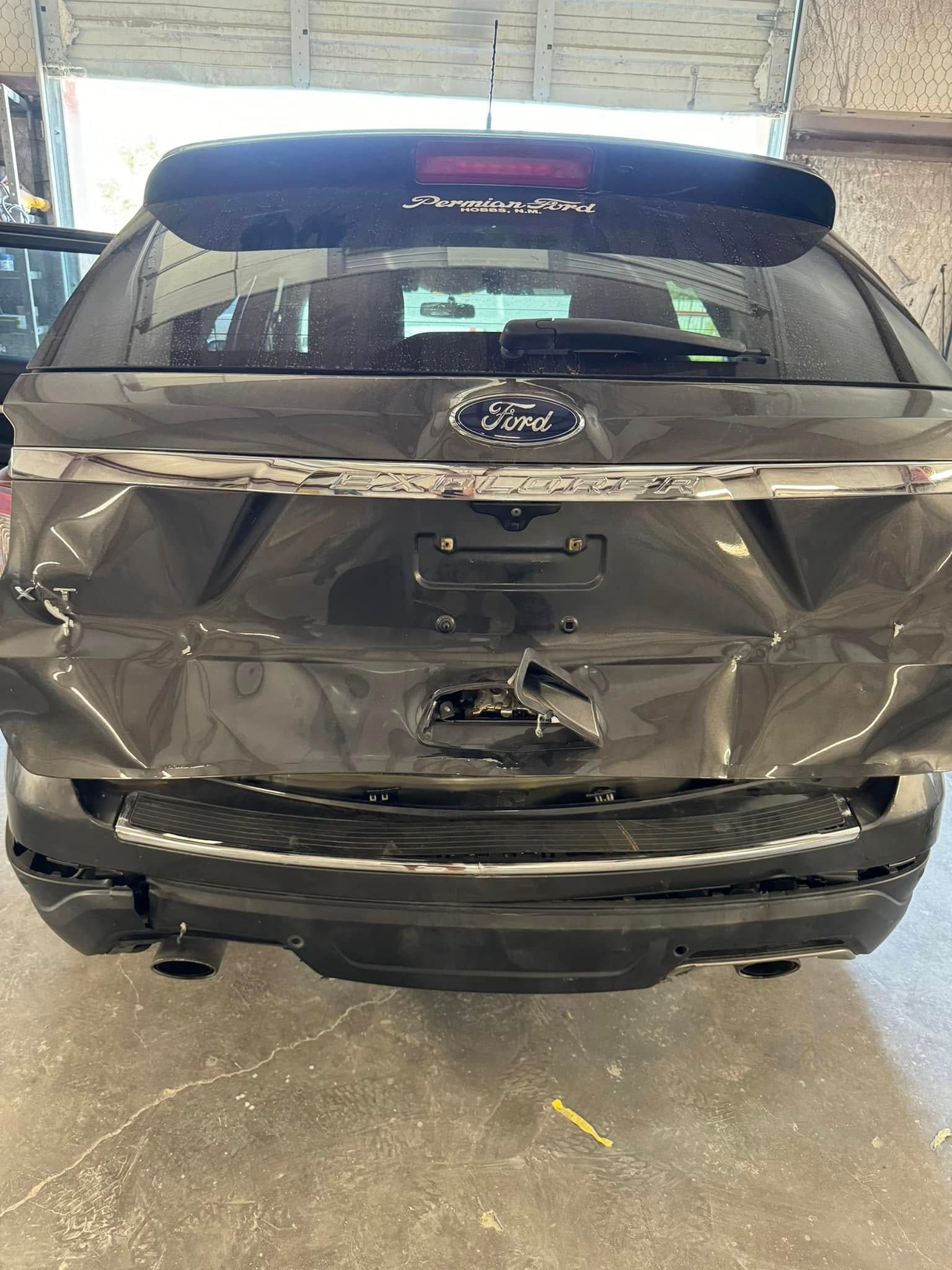 A damaged ford explorer is parked in a garage.