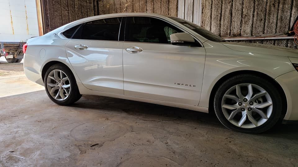A white car is parked in a garage next to a wooden wall.