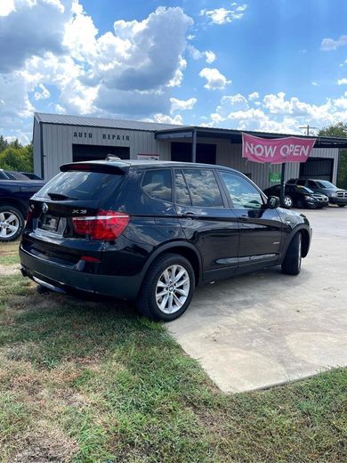 Black SUV parked in front of an auto repair shop with a 