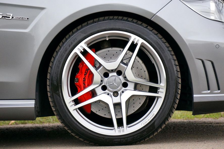 Silver car wheel with red brake caliper.