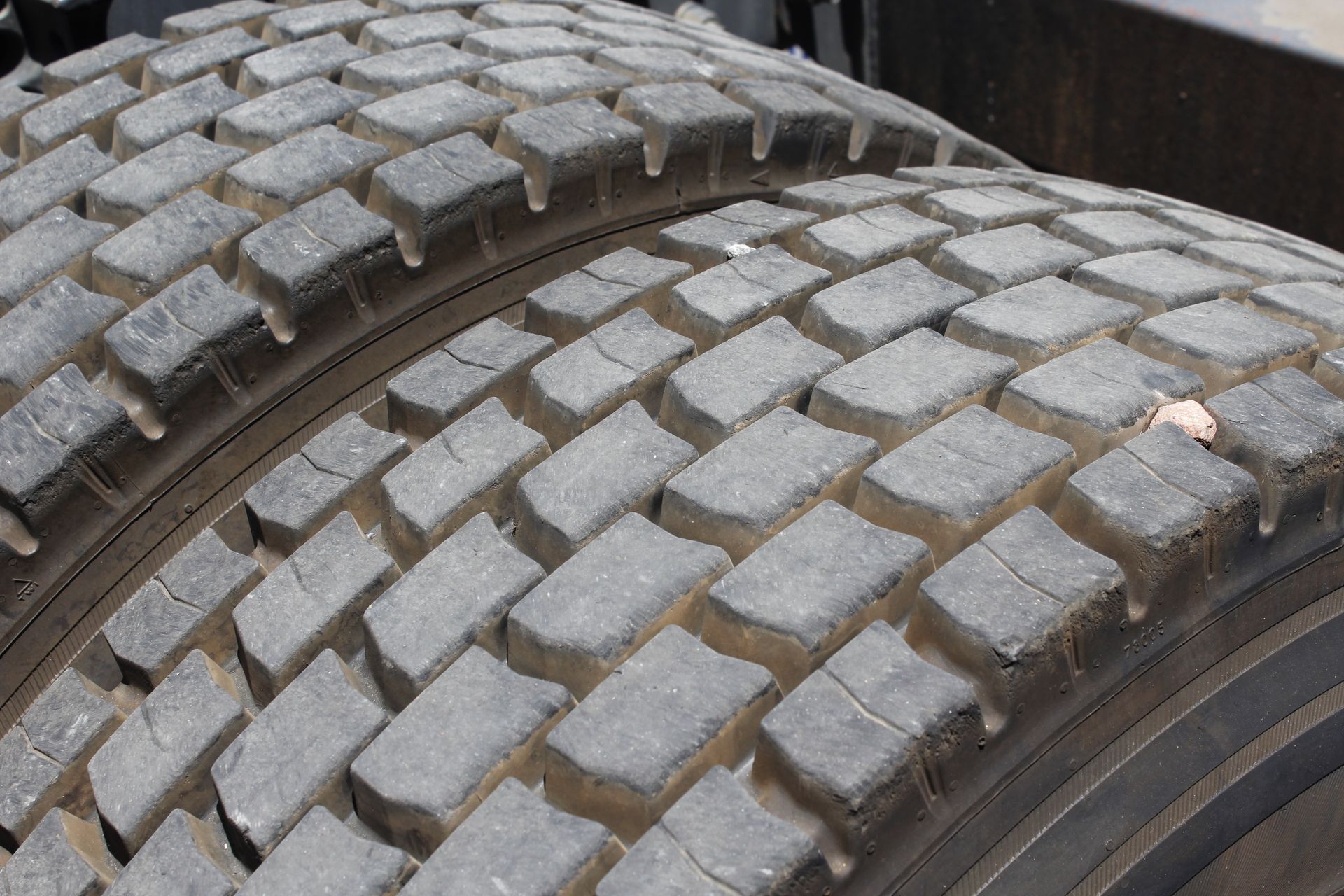 Tires stacked in a storage room with metal shelving and a grated floor.