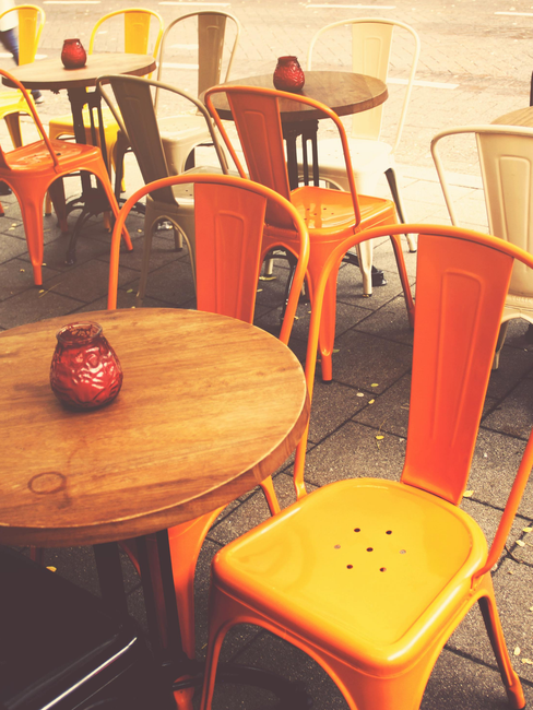 A row of orange chairs and tables outside of a restaurant