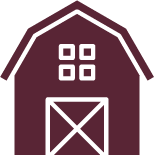 A burgundy barn with a white door and windows.