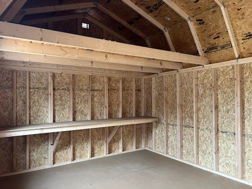 The inside of a wooden shed with shelves and a roof.