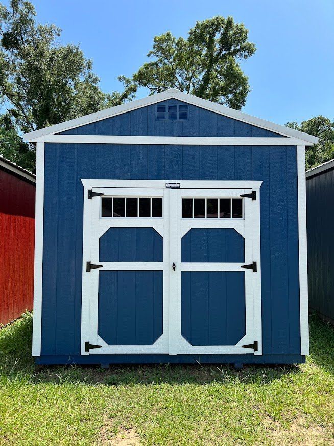 A blue and white shed is sitting on top of a lush green field.