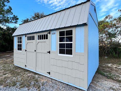 A blue and white shed with a metal roof and windows.