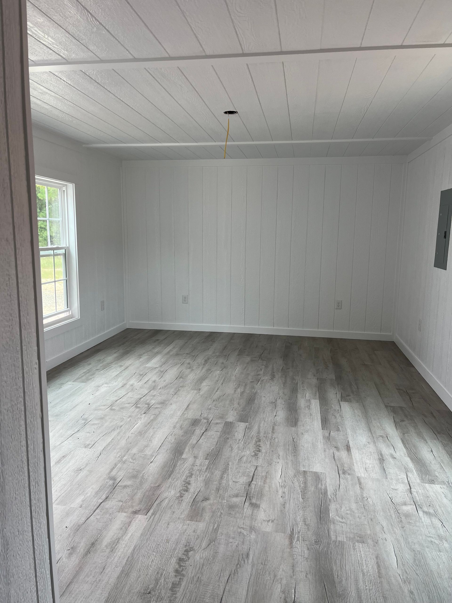 A large empty room with hardwood floors and white walls.