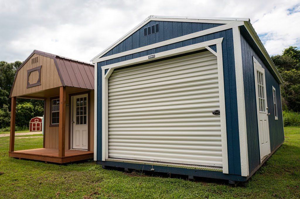 Two sheds are sitting next to each other in a grassy field.