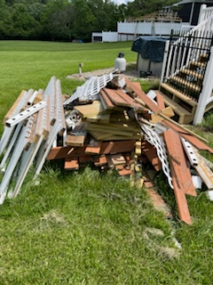 A pile of wood is sitting in the grass in front of a house.