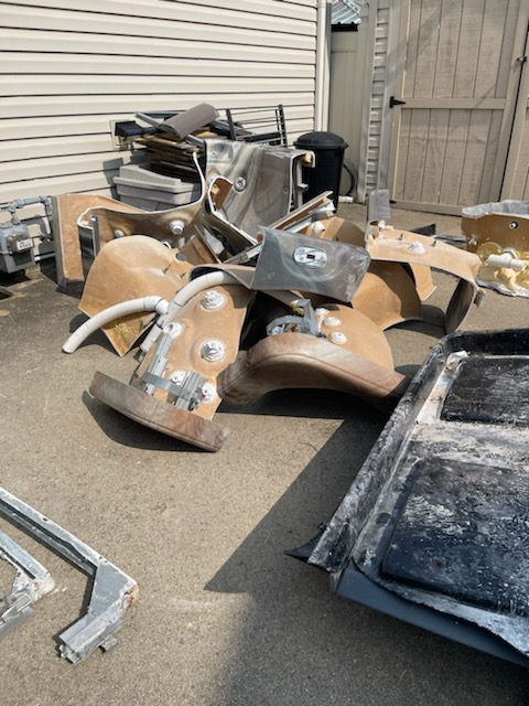 A pile of junk is sitting on the ground in front of a house.