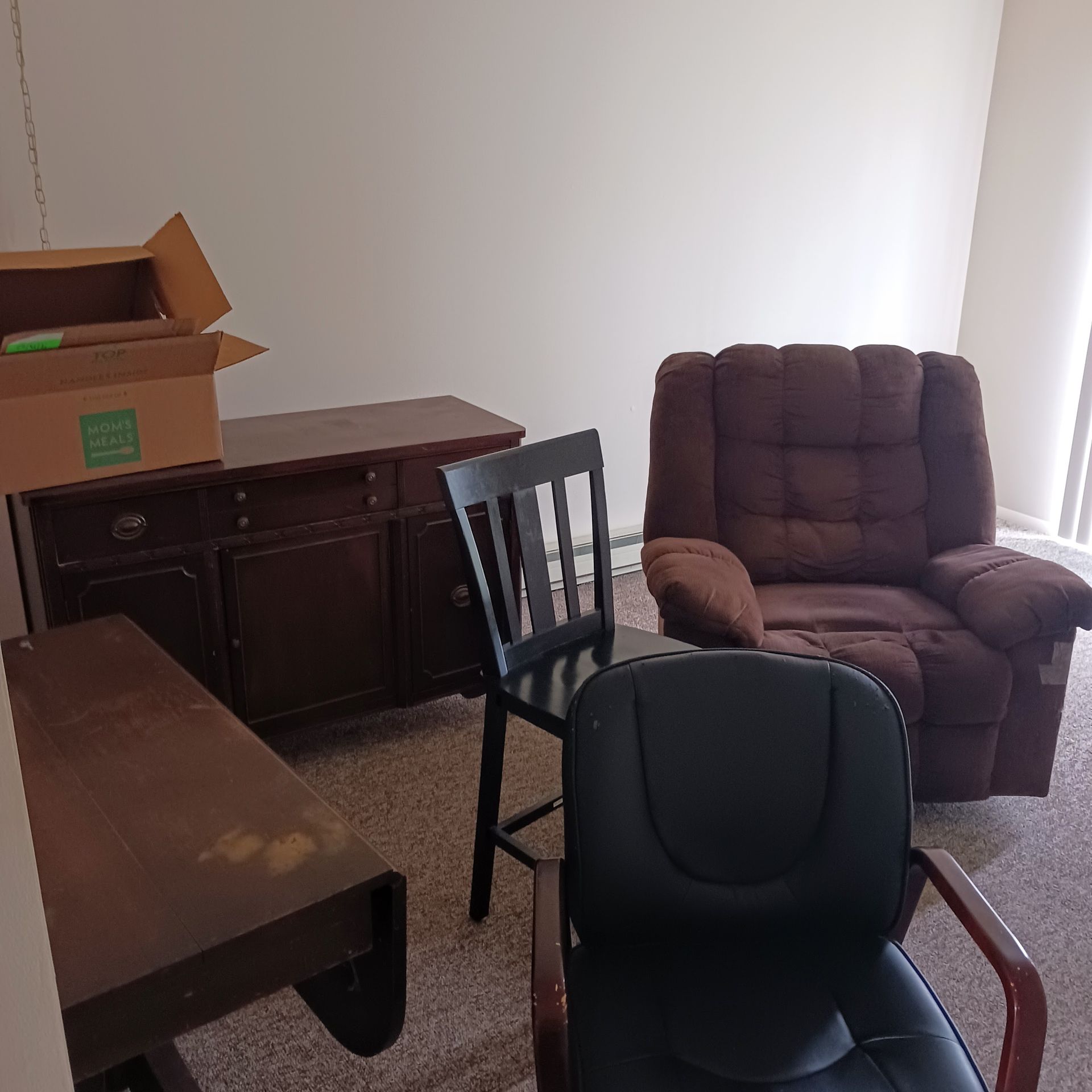 A room with a chair a desk and a box that says ' fragile ' on it