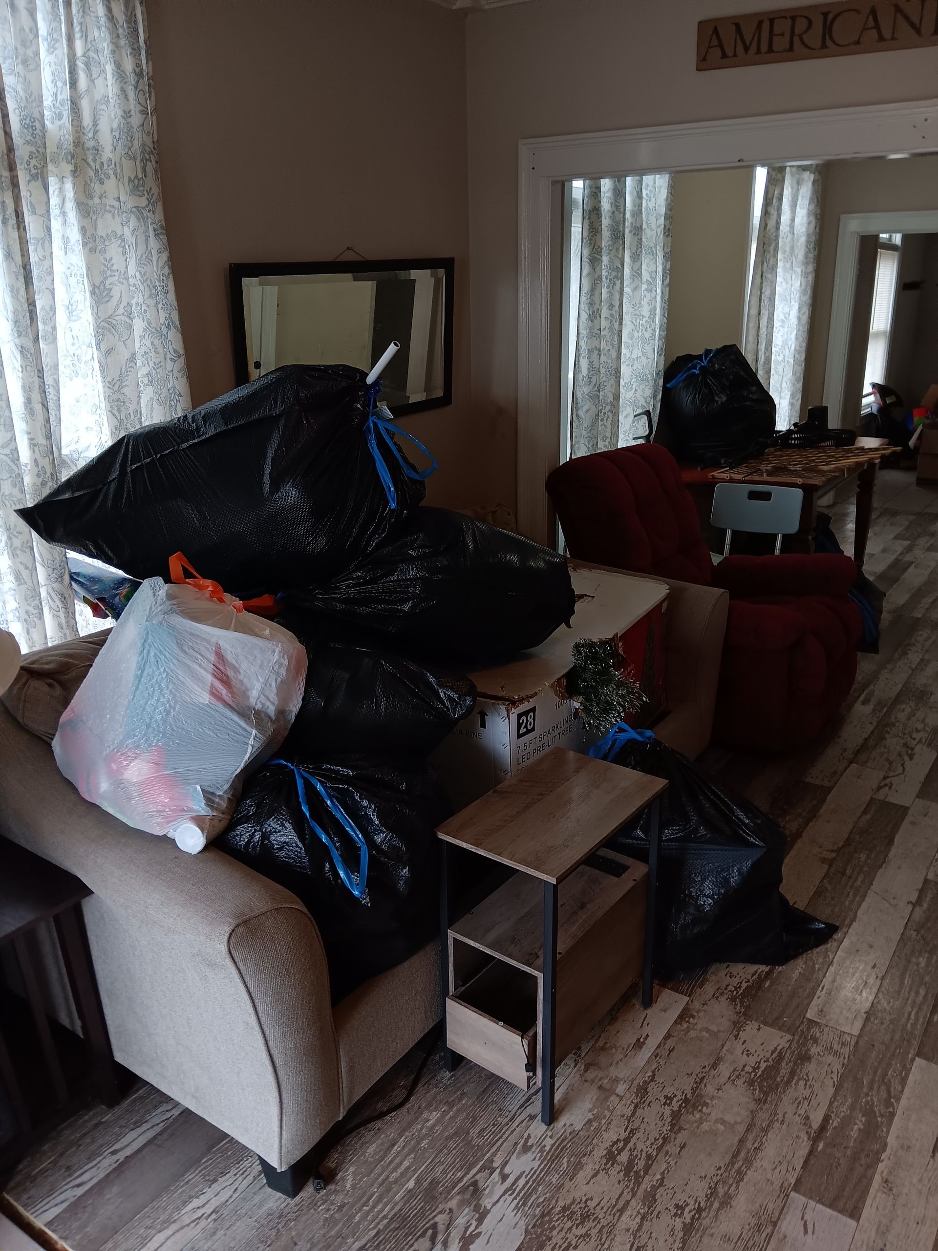 A living room filled with furniture and trash bags.
