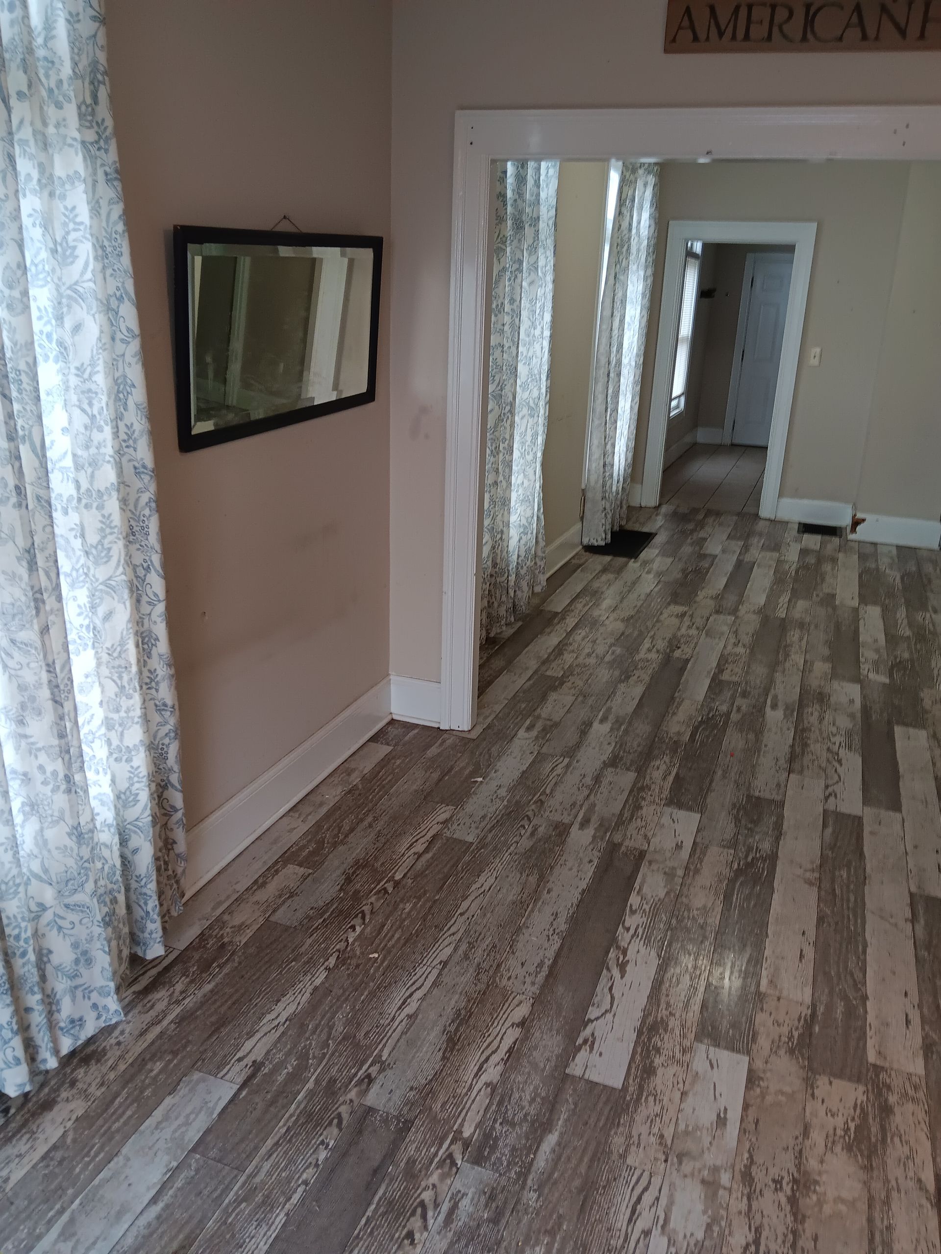 A living room with a wooden floor and a mirror on the wall.