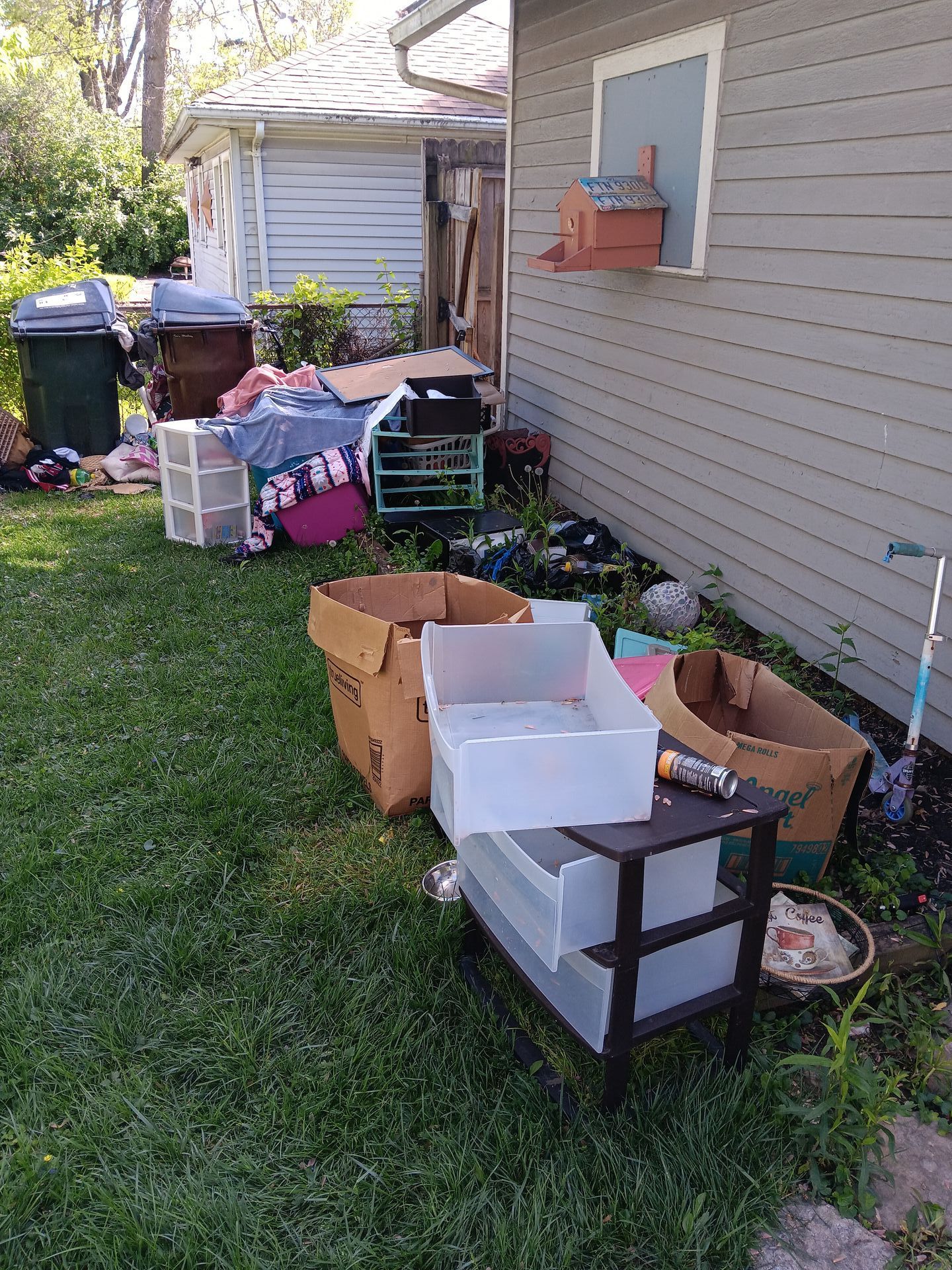 A bunch of boxes are sitting on the grass in front of a house.