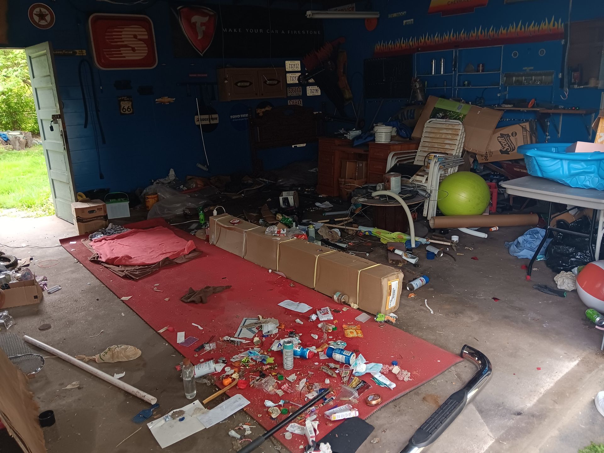 A messy room with a red rug and a green ball on the floor.