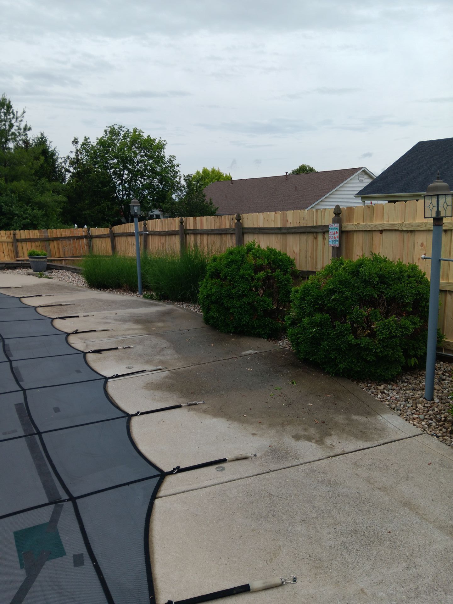 A wooden fence surrounds a swimming pool in a backyard.
