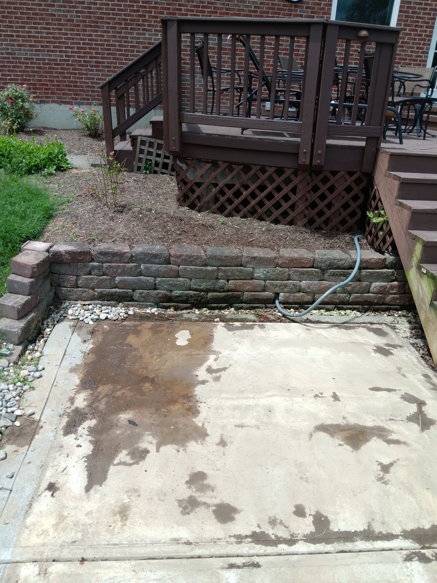 A concrete patio with a deck and stairs in the background.