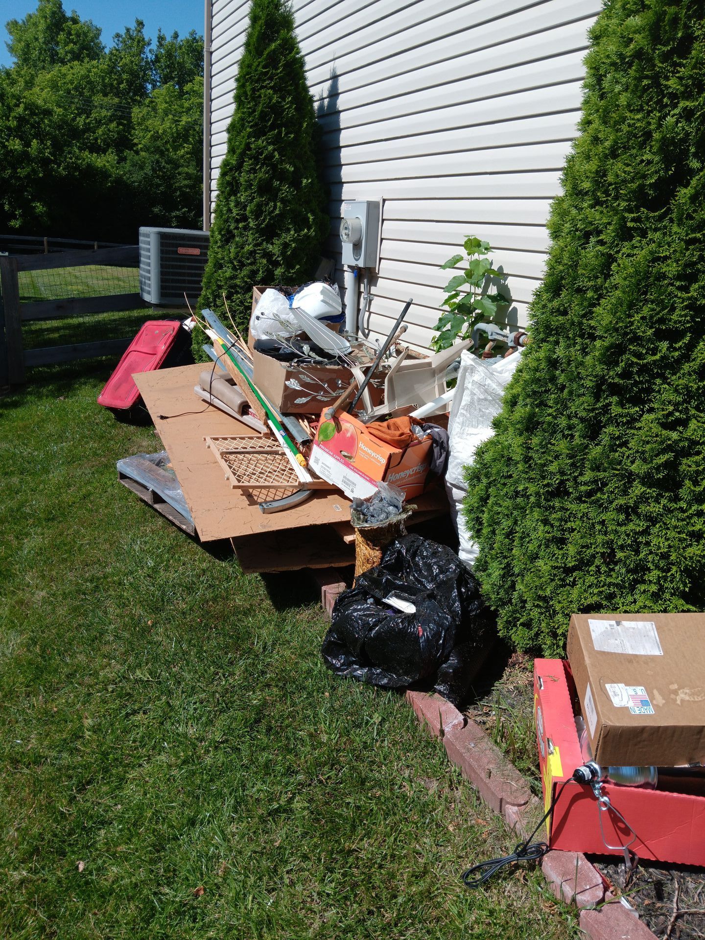 A pile of trash is sitting in the grass in front of a house.