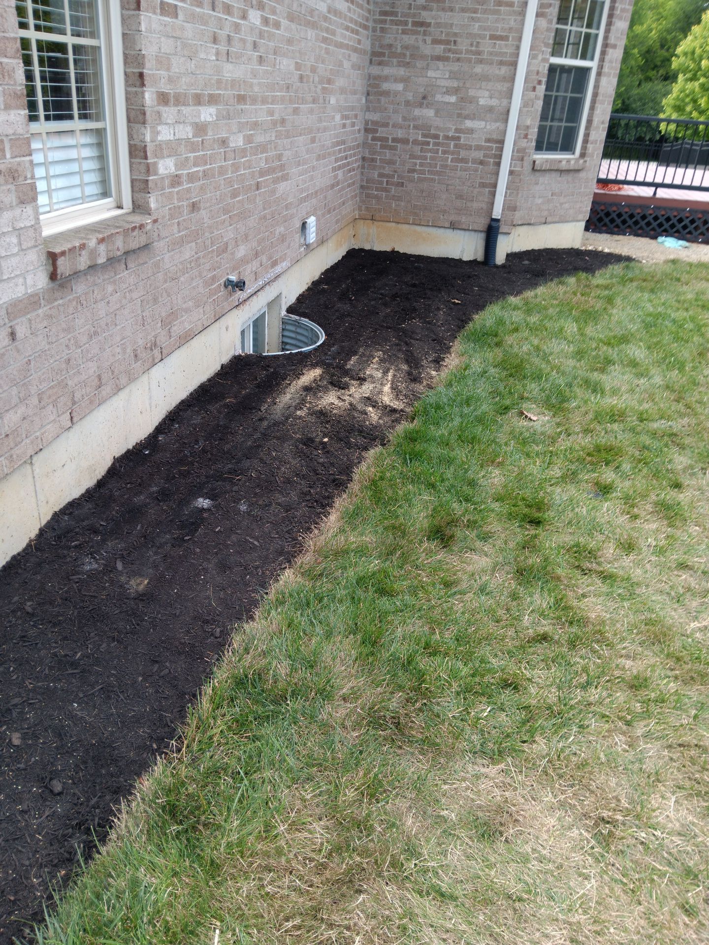 A brick house with a window and a drain on the side of it.