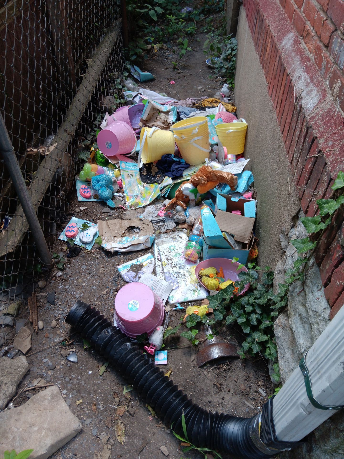 A drain pipe is laying on the ground next to a pile of trash.
