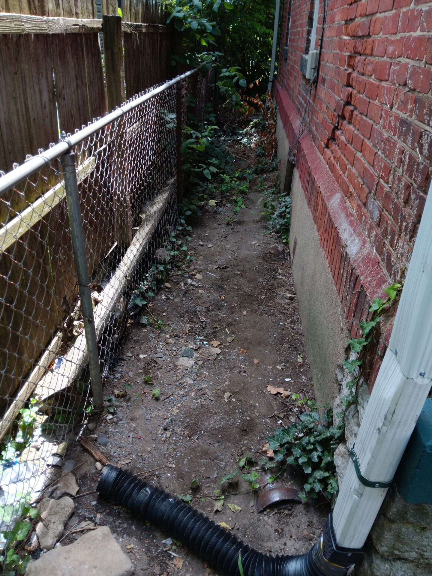 A chain link fence surrounds a dirt path leading to a brick building.