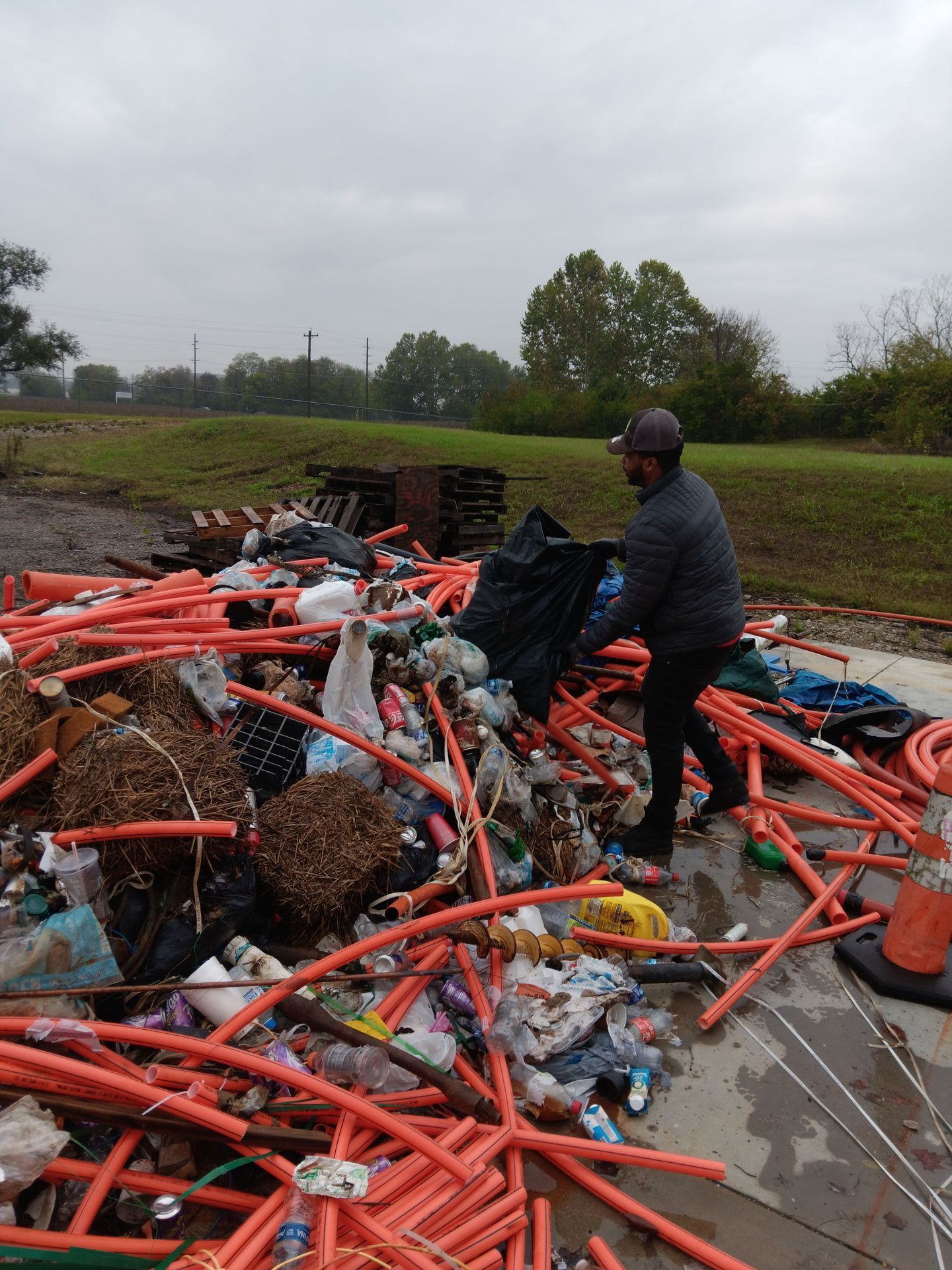 A man is standing in front of a pile of trash.