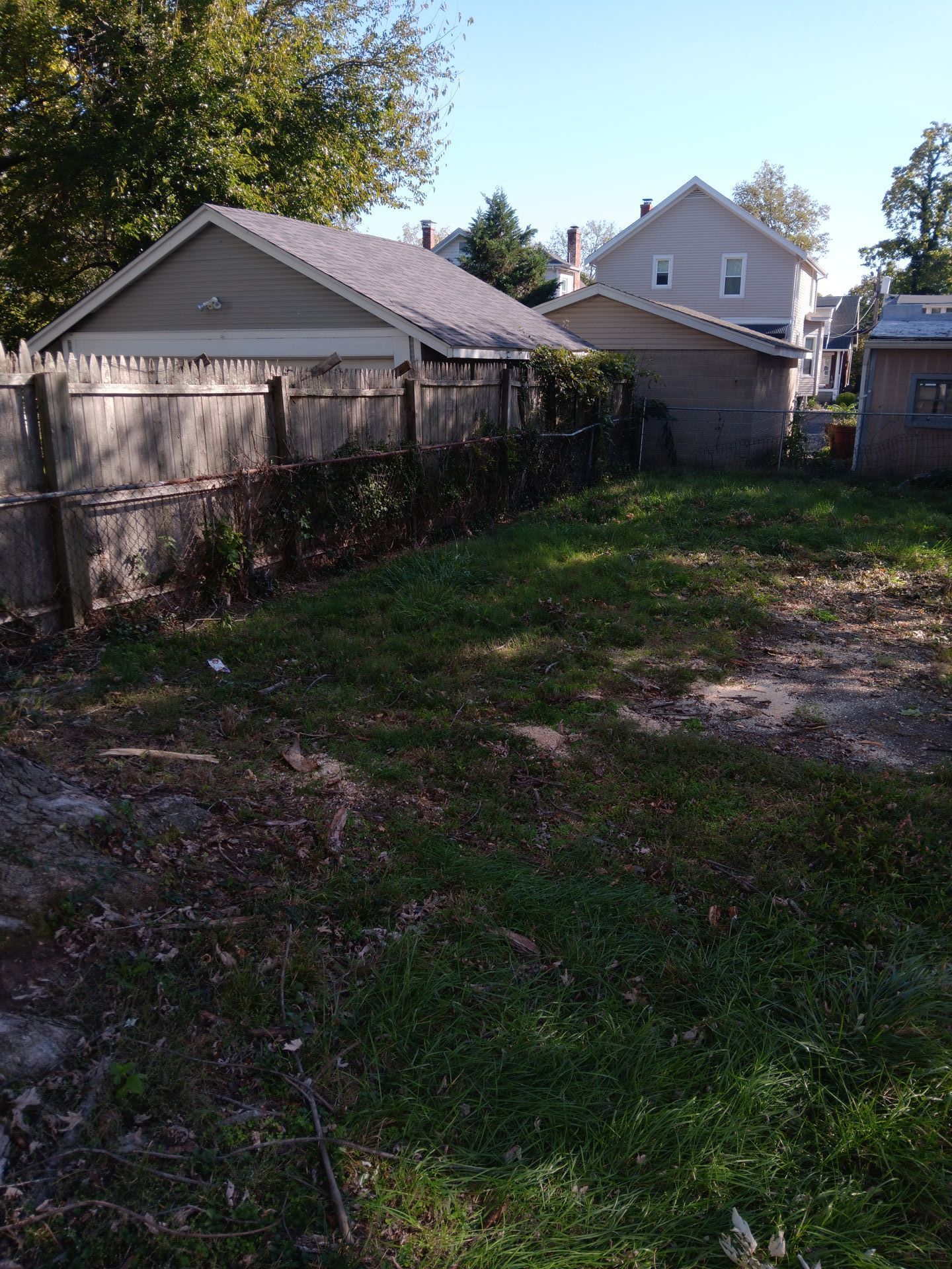 A backyard with a fence and a house in the background