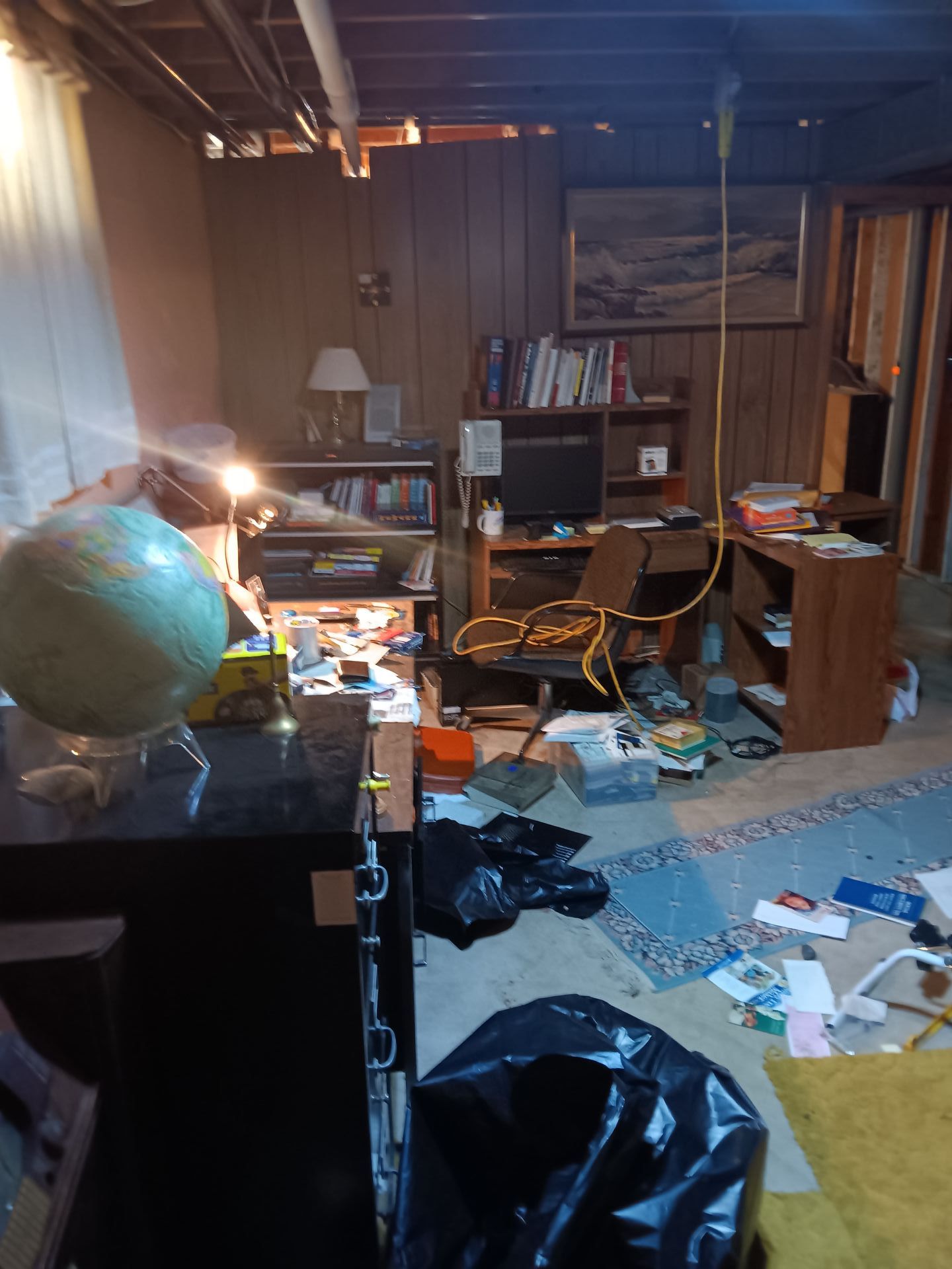 A messy basement with a globe on a desk.