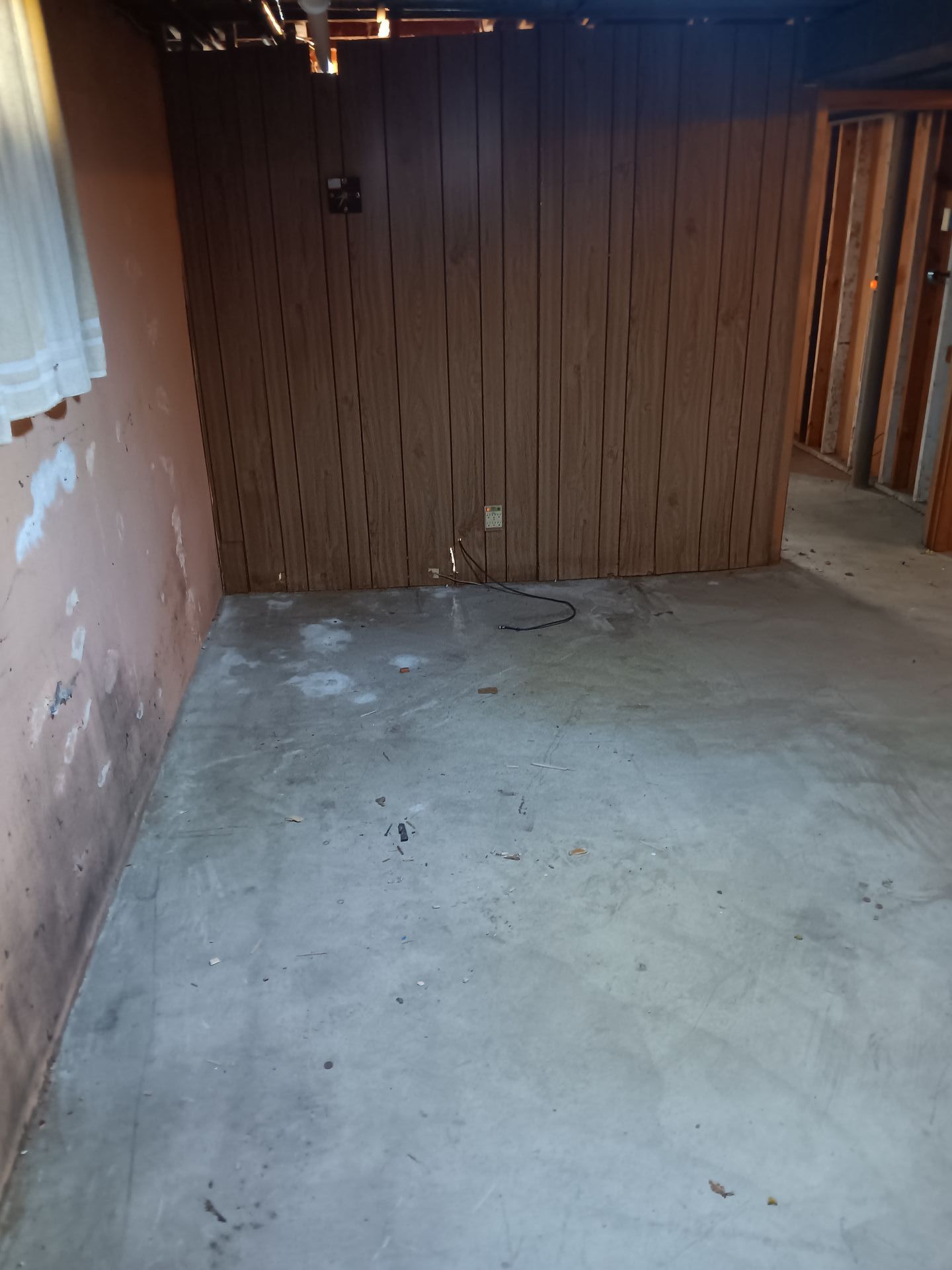 An empty room with a wooden wall and a concrete floor.