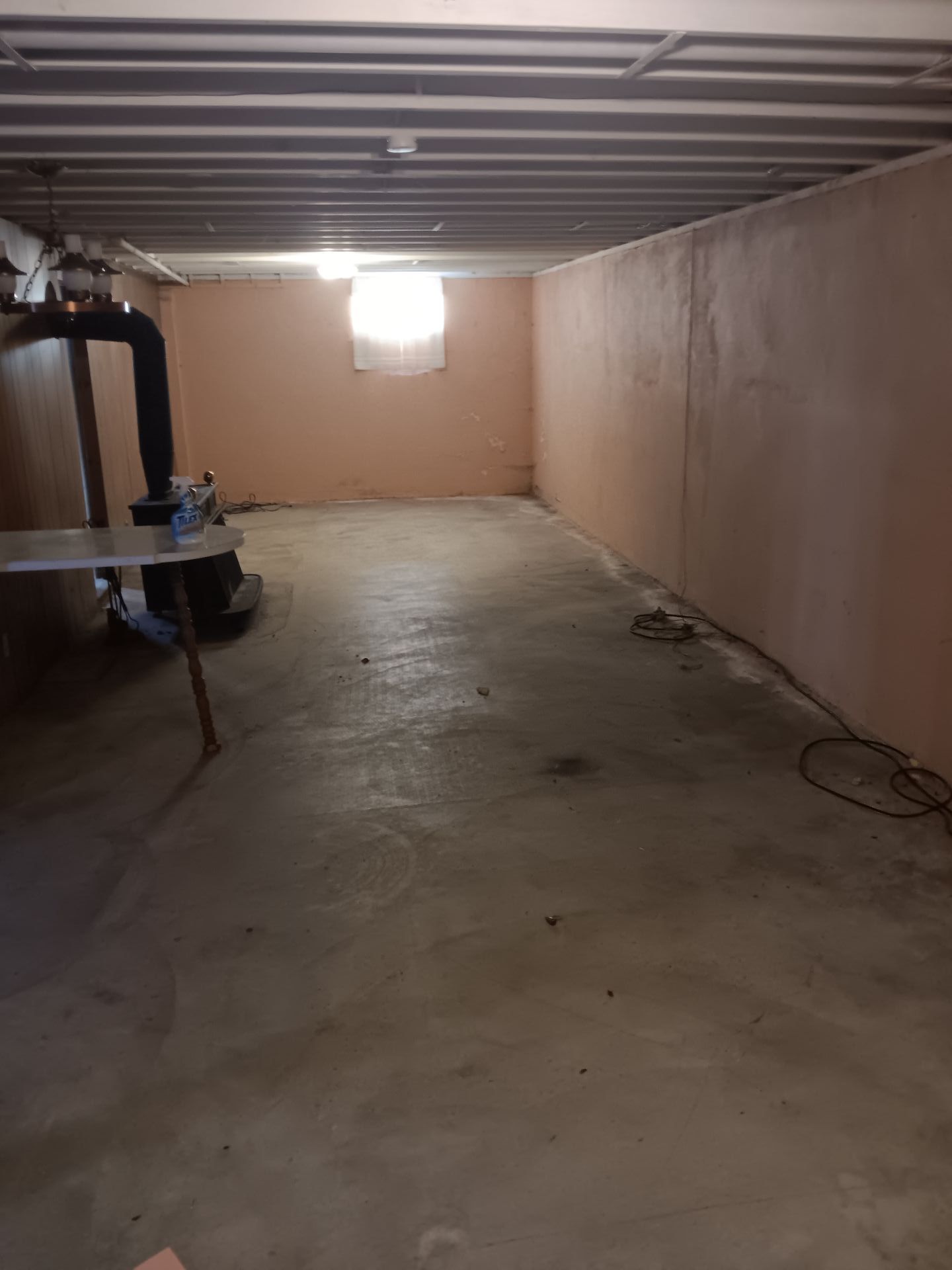 An empty basement with a table and a window.