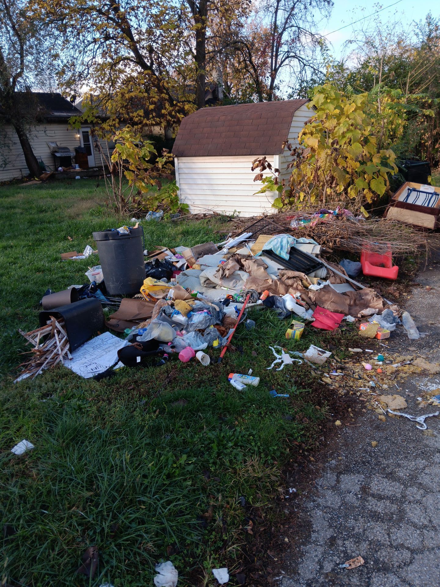 A pile of trash is sitting in the grass in front of a house.