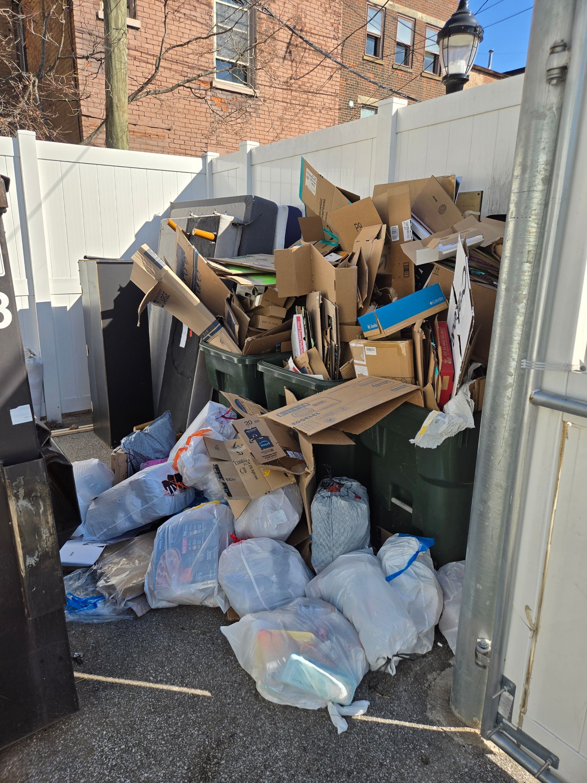 A dumpster filled with cardboard boxes and plastic bags