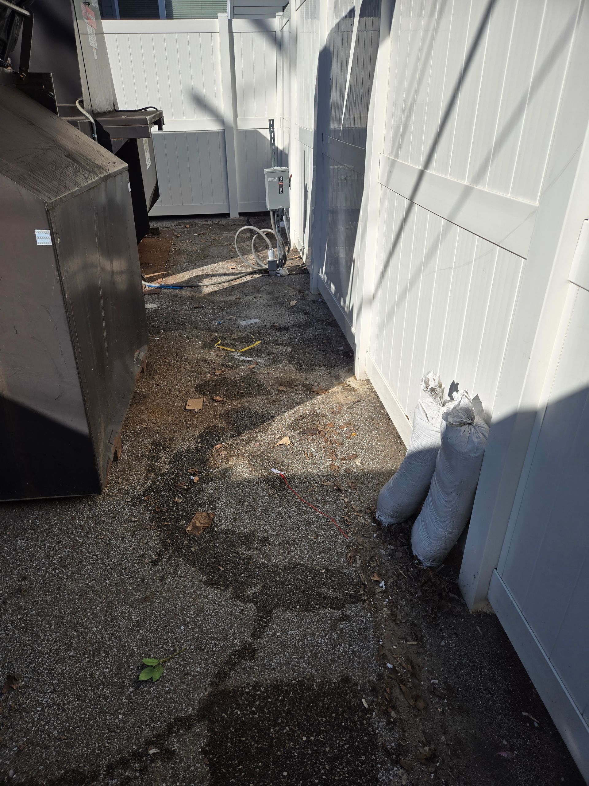 A couple of bags of sand are sitting on the ground next to a white fence.