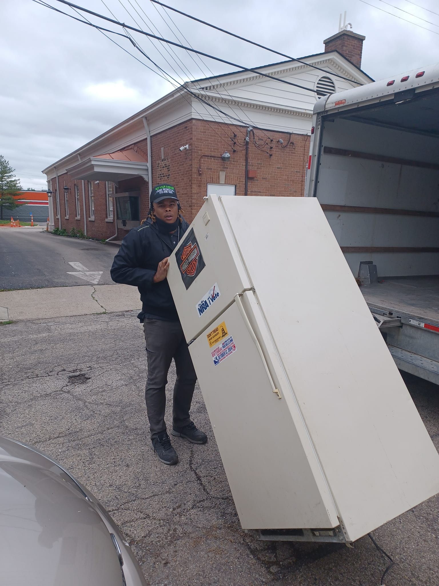 A man is carrying a refrigerator out of a truck.