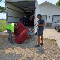 Two men are loading a red couch into a moving truck.