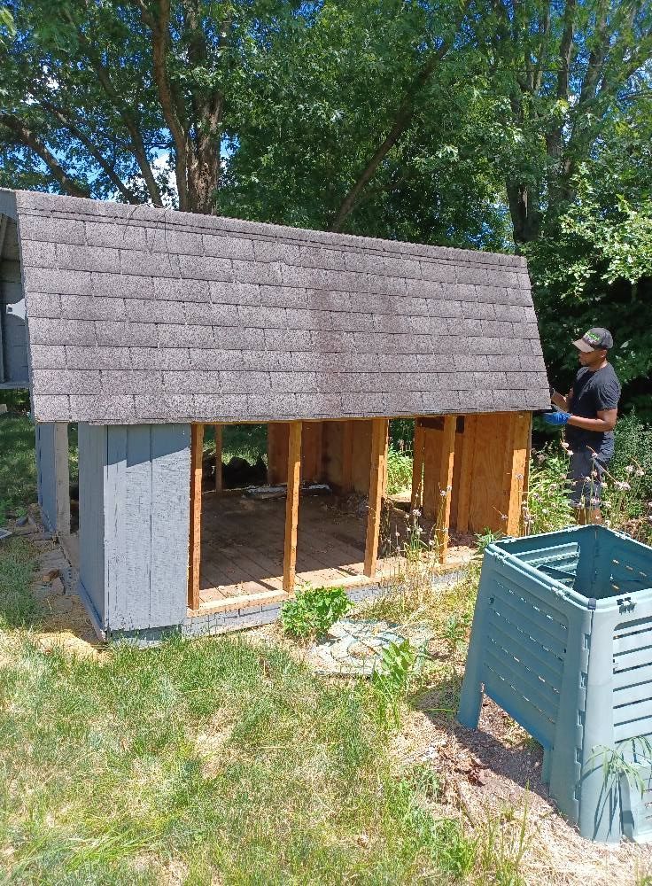 A man is working on a chicken coop in a backyard.