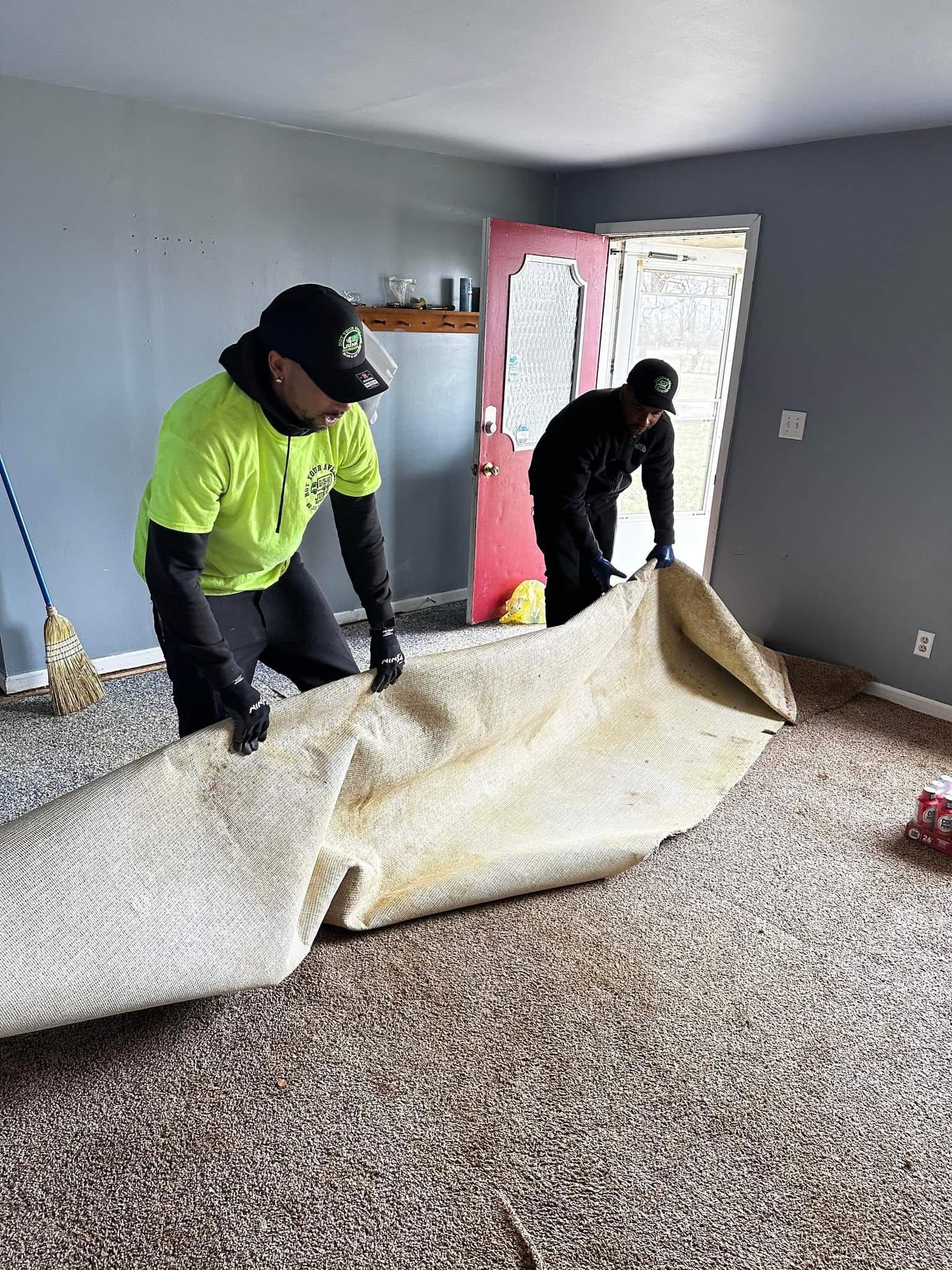 Two men are working on a carpet in a living room.